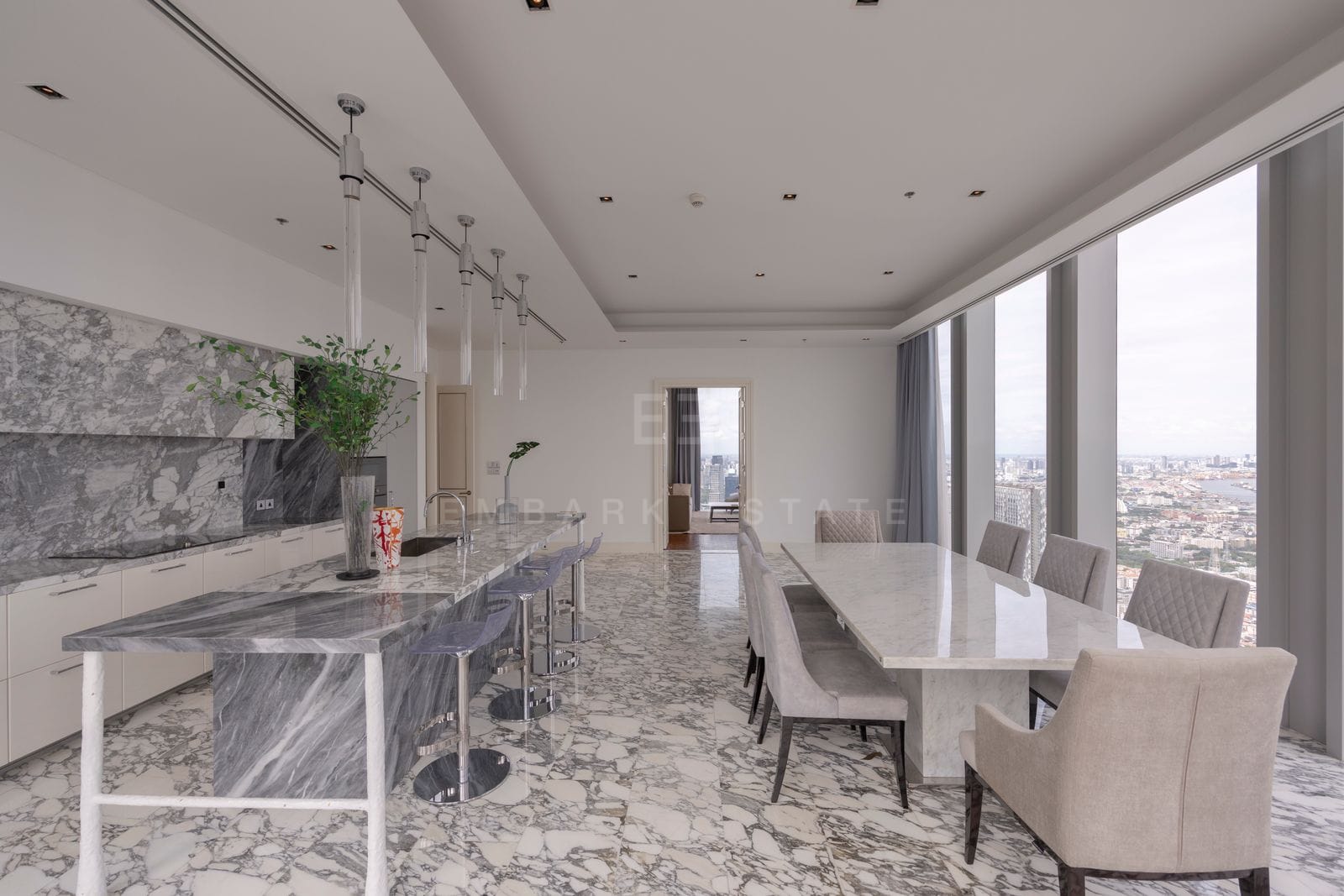 Dining table for ten beside the marble island at The Ritz-Carlton Residences Bangkok, with the city beyond the glass