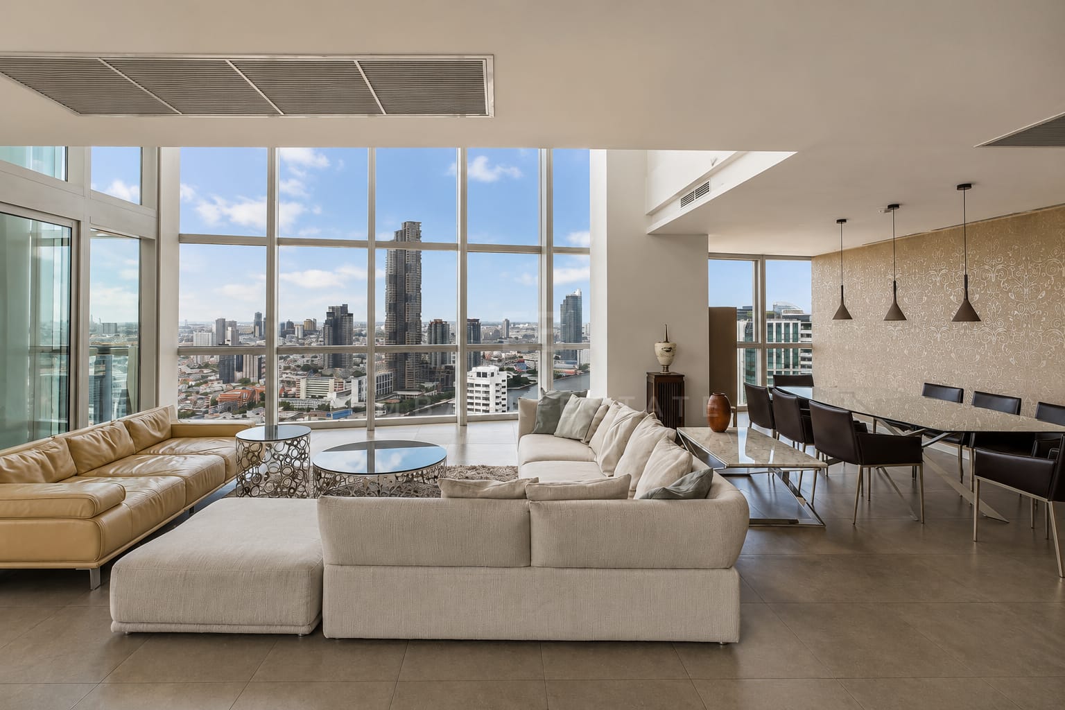 The living and dining room at The River, full-height glazing over the Chao Phraya with a glass dining table under its pendants