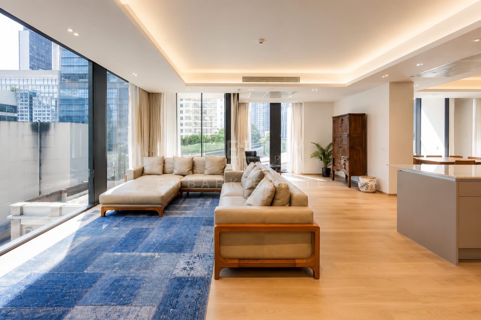The living room at Tonson One Residence, the sofa along the glazing with an antique timber cabinet and the kitchen island at the far end
