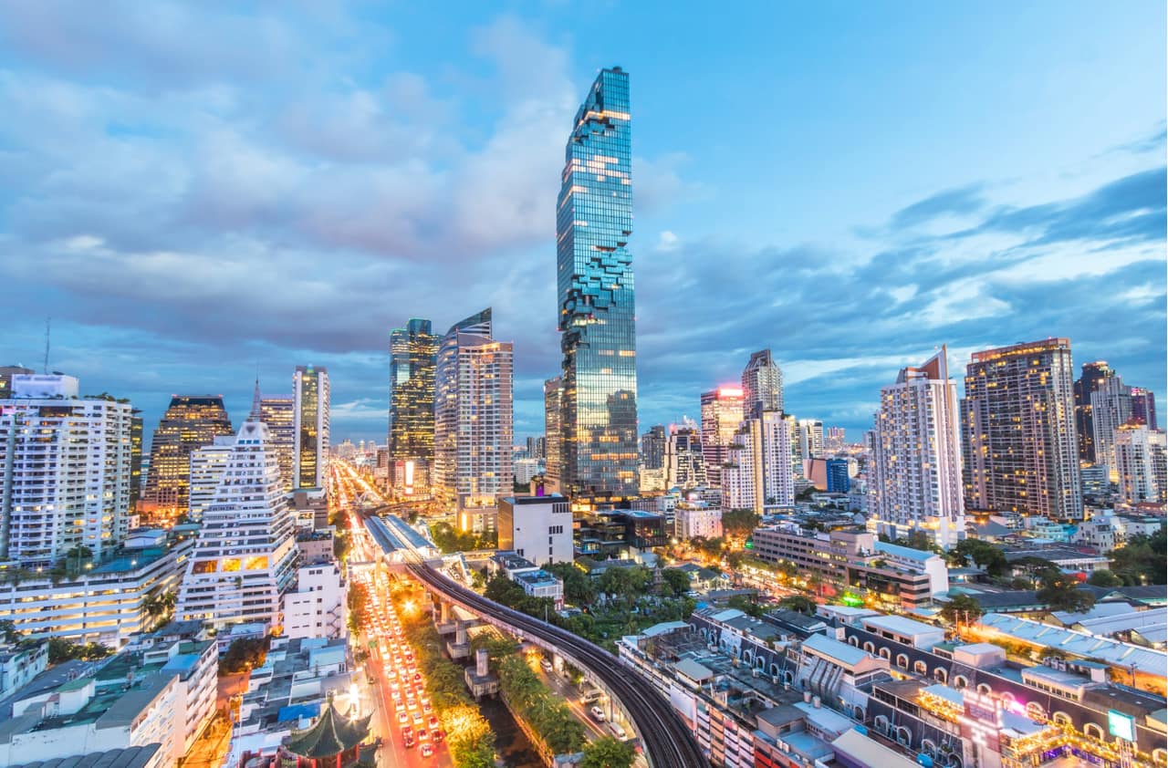The Sathorn corridor at dusk in central Bangkok, with King Power MahaNakhon rising over the Sathorn and Silom skyline