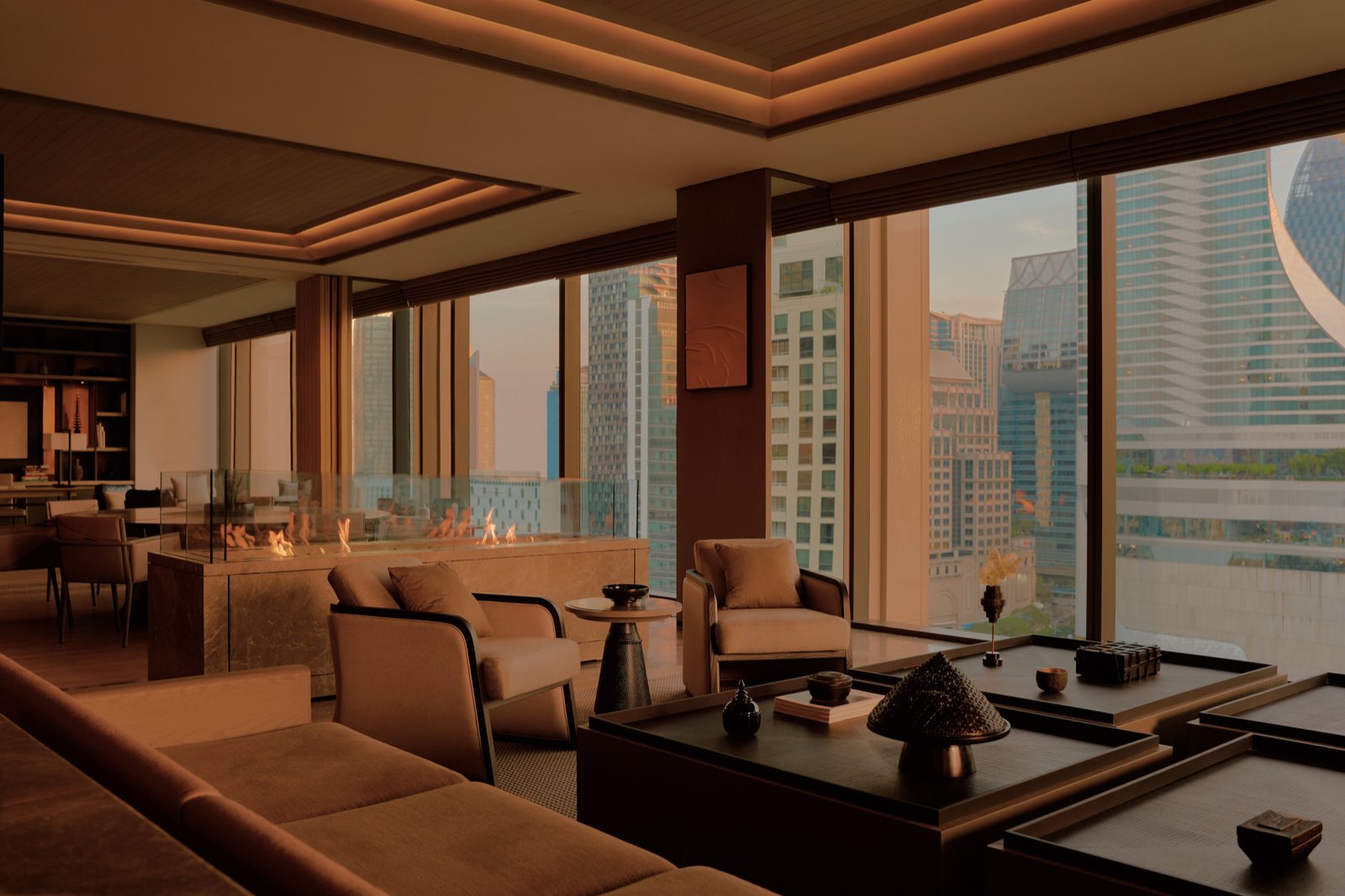 Aman Nai Lert Residences: Residence living room interior with a fireplace, lounge seating and floor-to-ceiling windows framing the Bangkok skyline